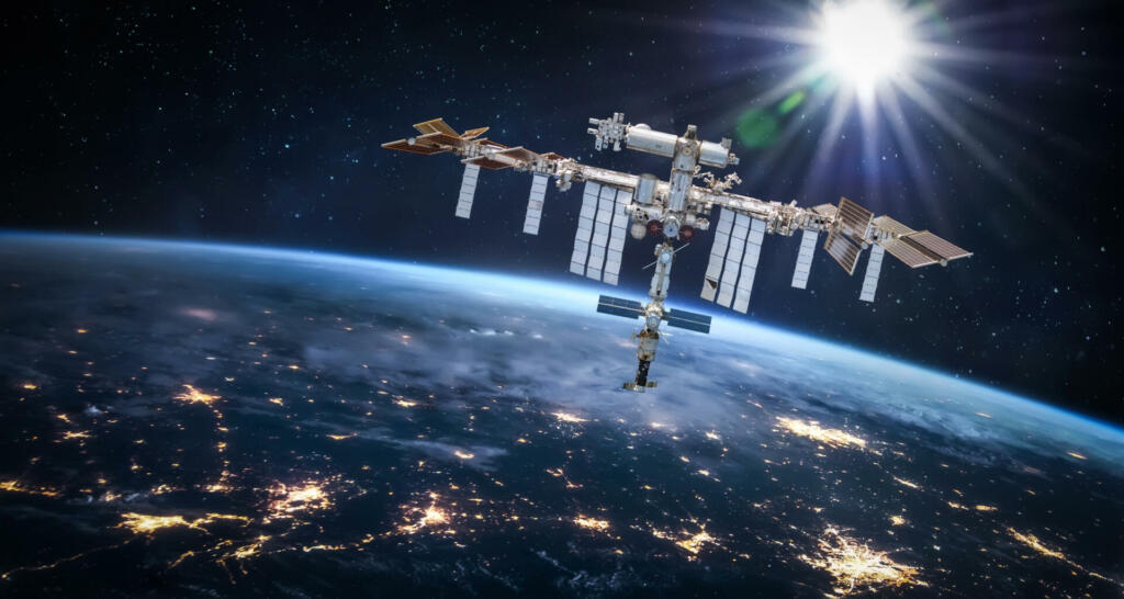 International space station in 2022 in outer space with Earth at night. ISS floating on orbit of nightly Earth planet. Elements of this image furnished by NASA (url:https://images-assets.nasa.gov/image/iss040e090540/iss040e090540~small.jpg https://www.nasa.gov/sites/default/files/styles/full_width_feature/public/thumbnails/image/iss066e080432.jpg)