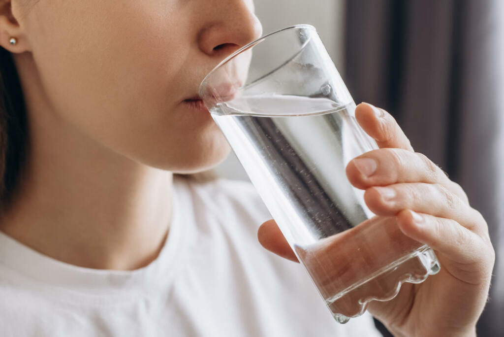 Side view close up of healthy young female drinking pure still water in morning. Caucasian lady enjoying healthy lifestyle daily habit, natural beauty, perfect skin body care aqua balance concept