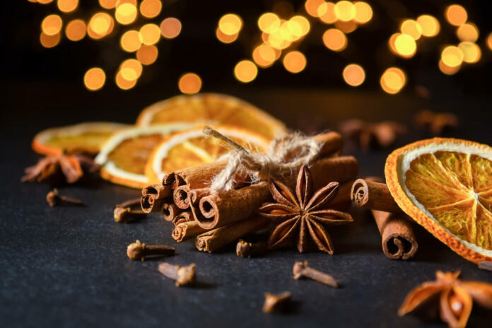 Traditional Christmas spices with dried orange slices on black background with defocus lights