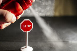 Using a red spray can with deodorant against a stop sign, environmental issue concept, soft focus close up