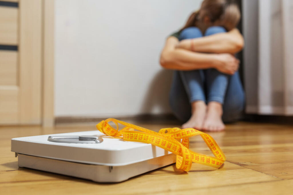 White scale and depression, upset and sad woman with measuring tape on wooden floor.