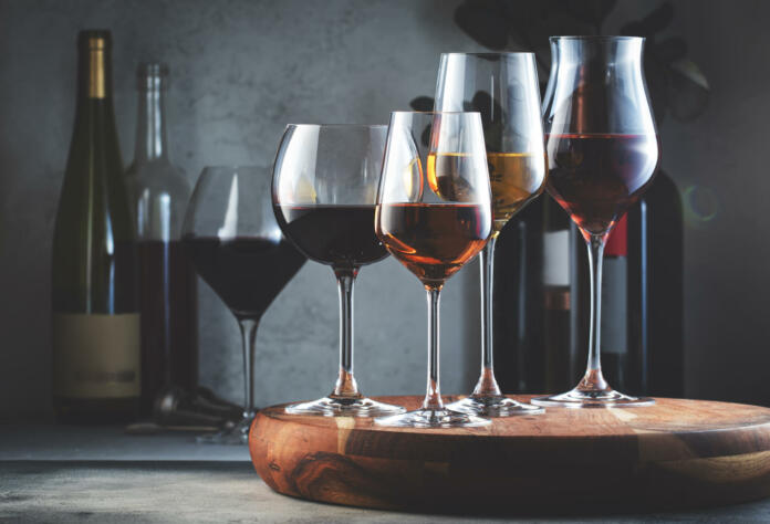 Wine glasses ans bottles assortment. Red, white, rose wines on gray table background. Wine bar, shop, tasting concept