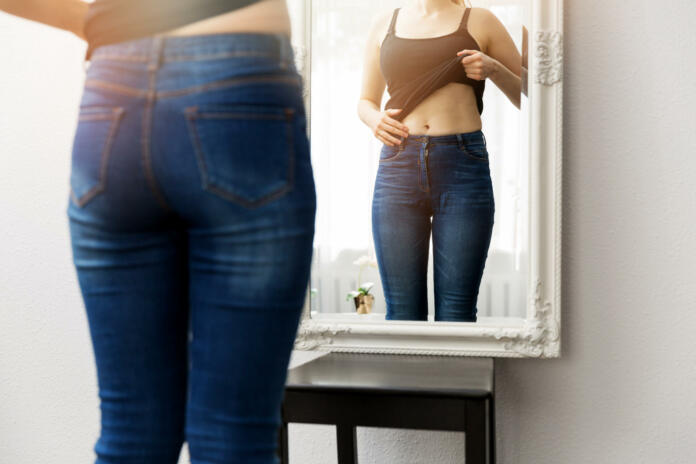 woman checking her body in front of mirror