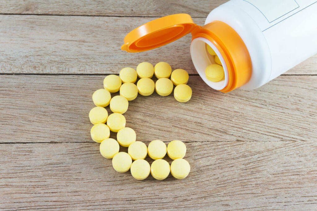 Yellow pills forming shape to C alphabet on wood background