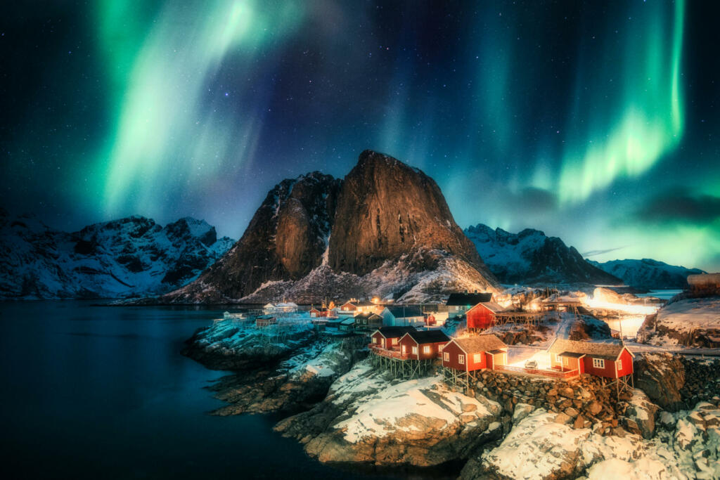 Aurora borealis, Northern lights over mountain with fishing village on coastline at Hamnoy, Lofoten islands, Norway