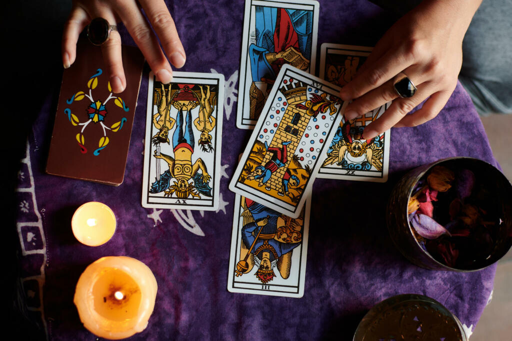 Close-up of a fortune teller reading tarot cards on a table with purple tablecloth