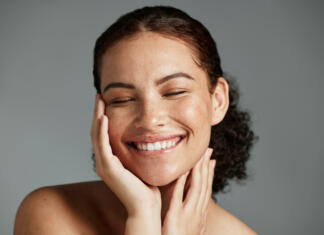 Kako nam lahko optimizem škodi? Face, beauty and satisfaction with a model black woman in studio on a gray background to promote natural skincare. Facial, wellness and makeup with an attractive young female happy with cosmetics