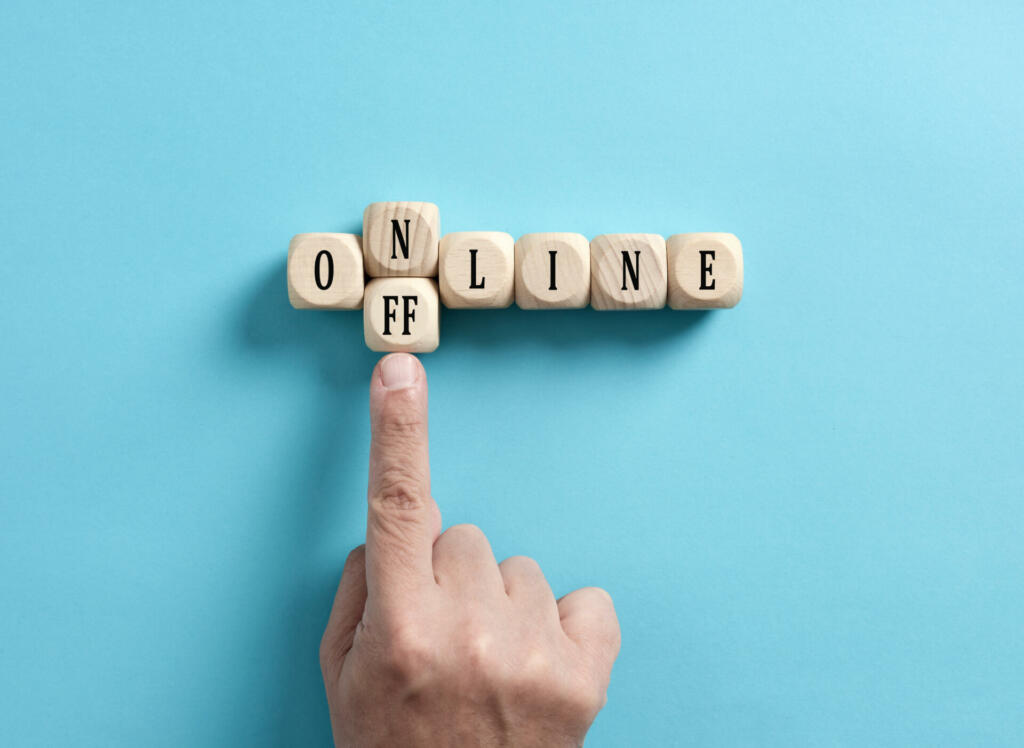 Going offline. To choose between online and offline. Digital detox. Male hand transforms the word online to offline on wooden cubes.