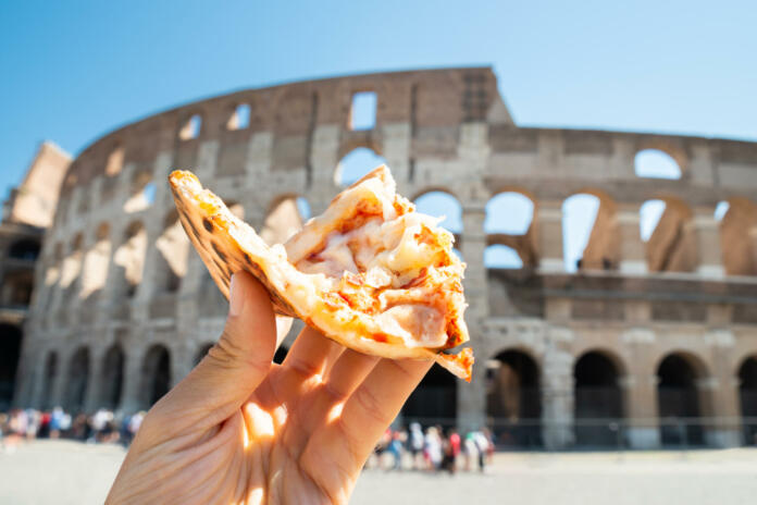 Hand Holding Slice Of Italian Pizza Near Colosseum, Rome