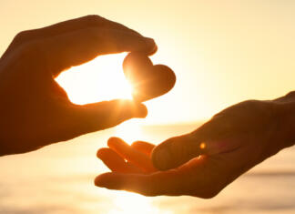 »Bodi luč za druge.« Pastoralno delo teologa v tujini Hand passing heart to another.