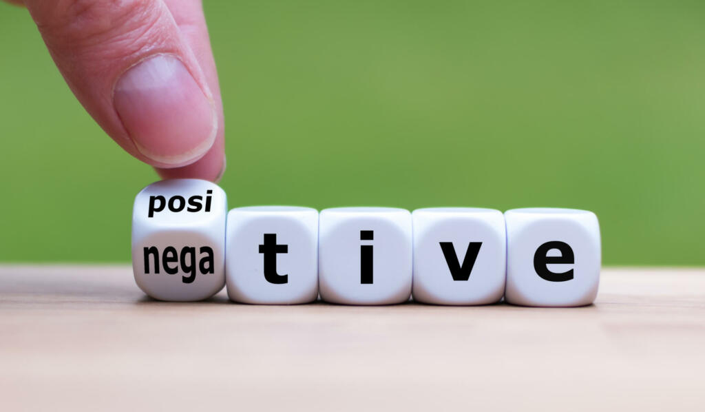 Hand turns a dice and changes the expression "negative" to "positive".