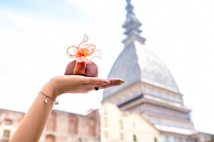 Holding italian chocolate with bow on famous cinema tower background in Turin city. Turin in Piedmont region in Italy is famous of its chocolate making