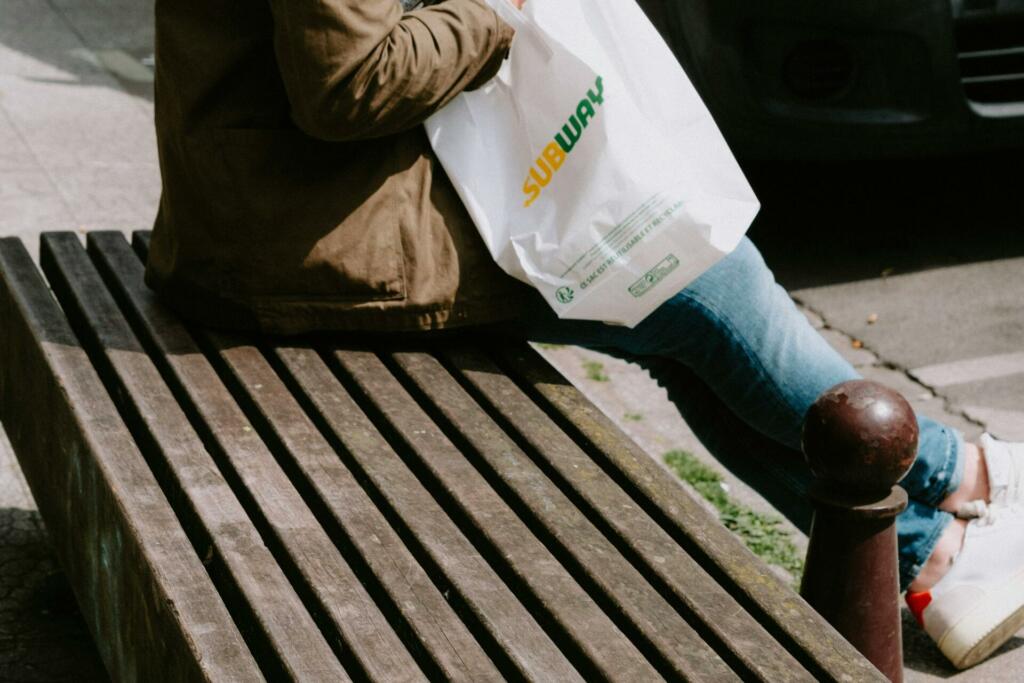 Moški sedi z vrečko Subwaya