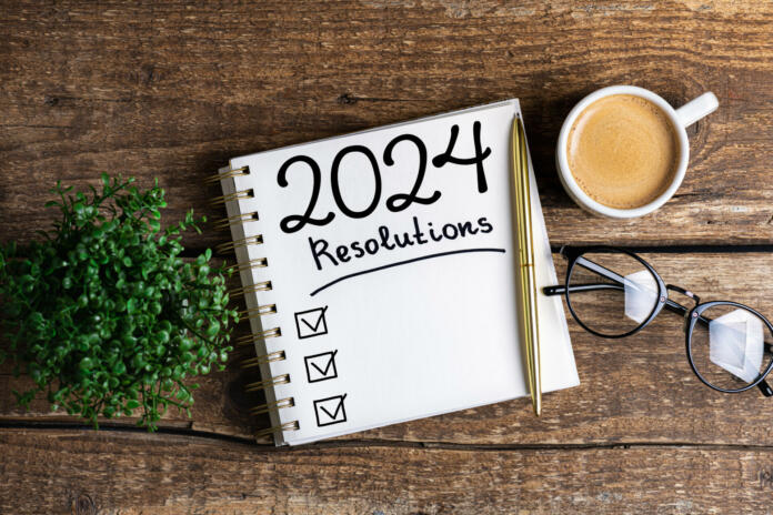 New year resolutions 2024 on desk. 2024 resolutions list with notebook, coffee cup on table. Goals, resolutions, plan, action, checklist concept. New Year 2024 template, copy space