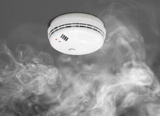 Kako delujejo senzorji za detekcijo plina? smoke detector of fire alarm in action, gray background with dense fog