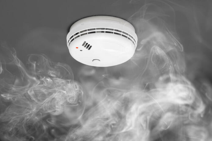 smoke detector of fire alarm in action, gray background with dense fog