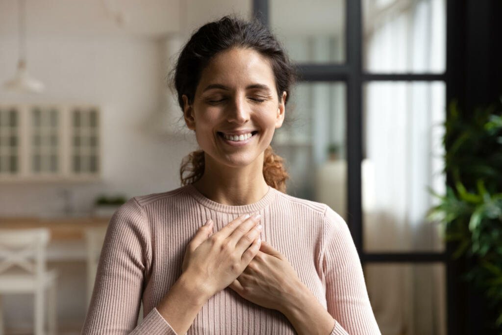 Thank you my God. Happy peaceful millennial hispanic lady stand alone with closed eyes keep hands close to heart hope pray in mind. Emotional young woman express deep gratitude impressed by good deed