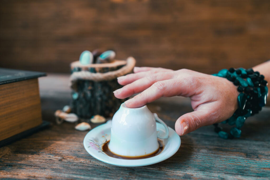 woman toch the mug before telling fortune with turkish coffee cup