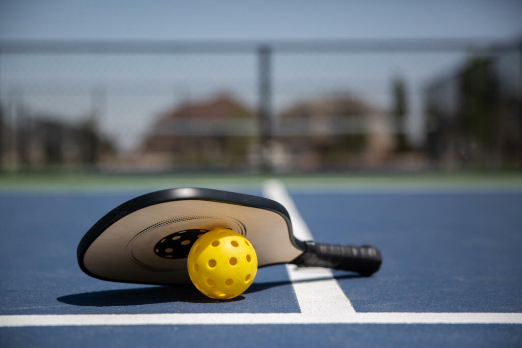 Young caucasian boy playing pickle ball on a hot summer day.