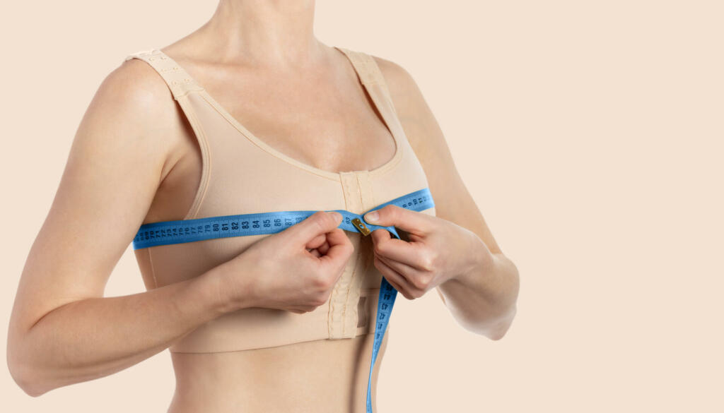 Young woman taking measurements after breast augmentation. Copy space.