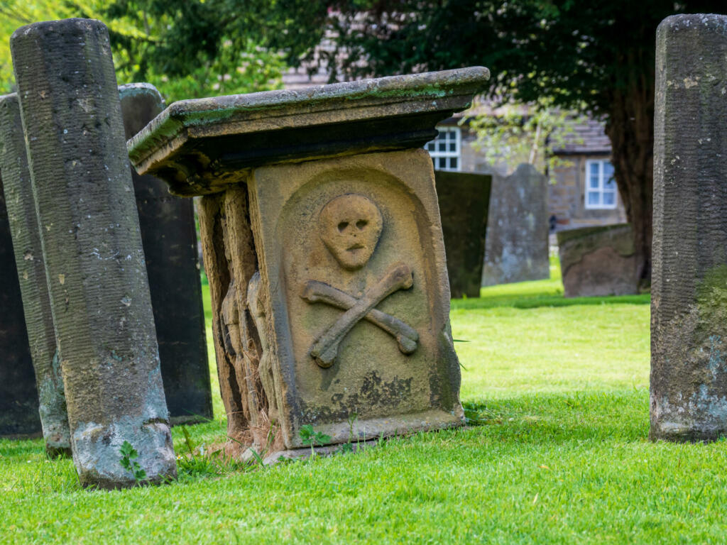 Eyam village church grave yard skull and cross bones carving on the grave stone from the bubonic plague era
