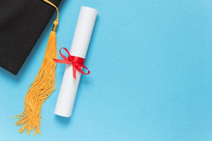 Graduation top view concept. Academical hat and diploma on blue background. Copy space