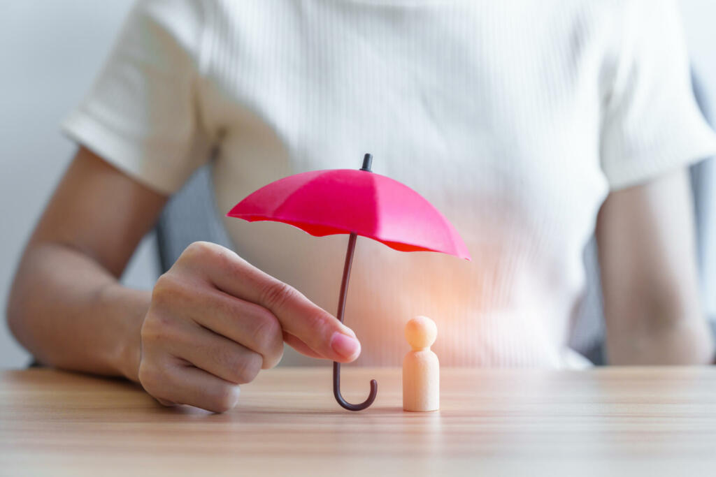 hand holding red umbrella and cover wood man. People protect, Life Insurance, health and leadership Concepts