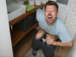 Man suffering from hemorrhoids screams on toilet in toilet. Internal hemorrhoids causes symptoms and treatment