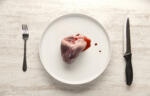 Pork heart on a white plate with fork and knife