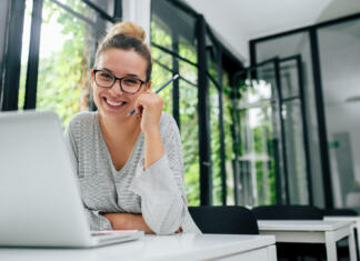 To so 3 najbolj inteligentna astrološka znamenja: Si med njimi? Portrait of smiling young female student in eyeglasses sitting in modern library.