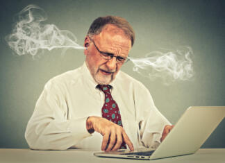 Zloglasni pisateljski spori, ki nas lahko učijo še danes Stressed elderly old man using computer blowing steam from ears. Frustrated guy sitting at table working on laptop isolated on gray wall background. Senior people and technology concept