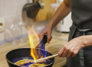 Vroča sladica, ki je ne smeš zgrešiti! Recept za ogenj in led Woman preparing caramelized banana flambe with cognac in frying pan and sets fire