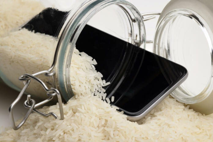 A wet smartphone is dried in rice and glass bottle on white background