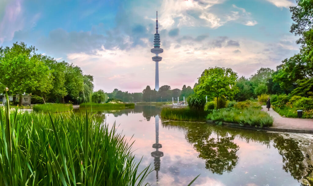 Beautiful view of flower garden in Planten um Blomen park with famous Heinrich-Hertz-Turm radio telecommunication tower in the background at dusk, Hamburg, Germany