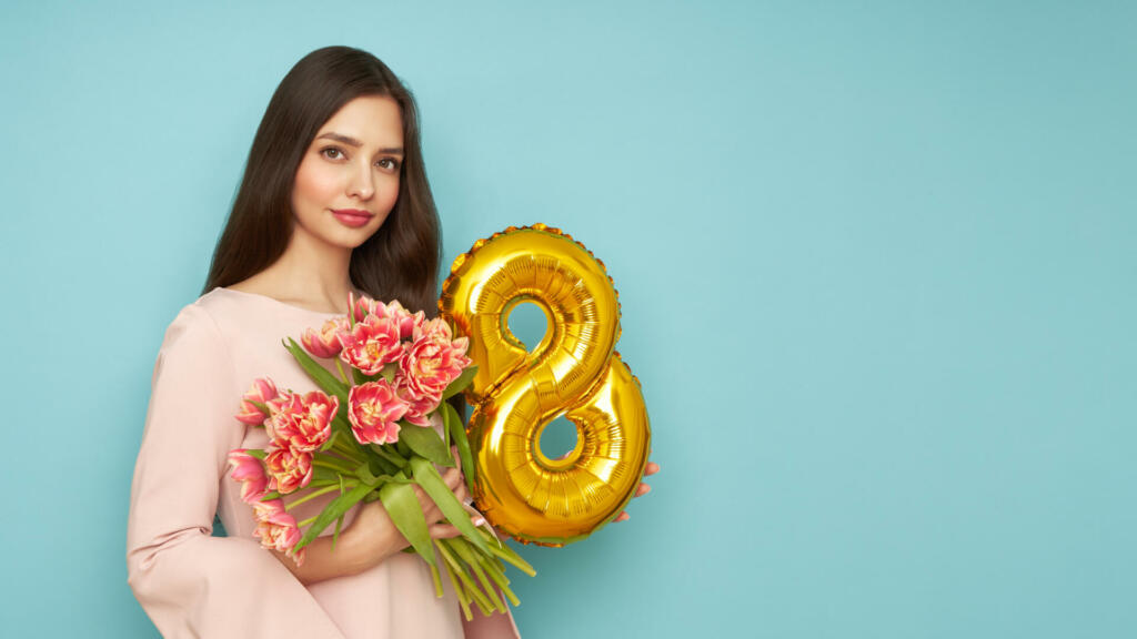 Beautiful young woman hold bouquet of tulips flowers and balloon number 8, rejoices spring holiday. Women's Day on March 8th