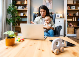 Vrnitev na faks kot starš: Vse, kar moraš vedeti Business woman on maternity leave. Mother with newborn baby working from home using laptop. Female professional work at home office remotely video call conference on computer.