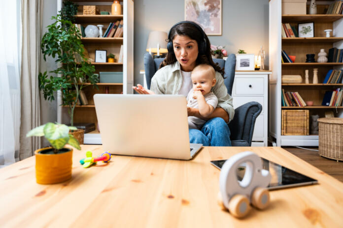 Business woman on maternity leave. Mother with newborn baby working from home using laptop. Female professional work at home office remotely video call conference on computer.