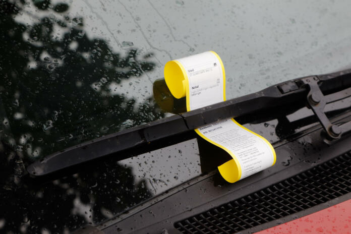 Norwegian parking ticket attached to the windscreen wiper on a car displays information about location and cause.