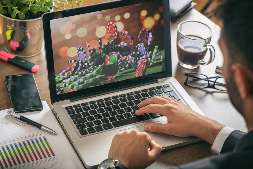 Online gambling concept. Man at work - Casino chips on a computer screen.