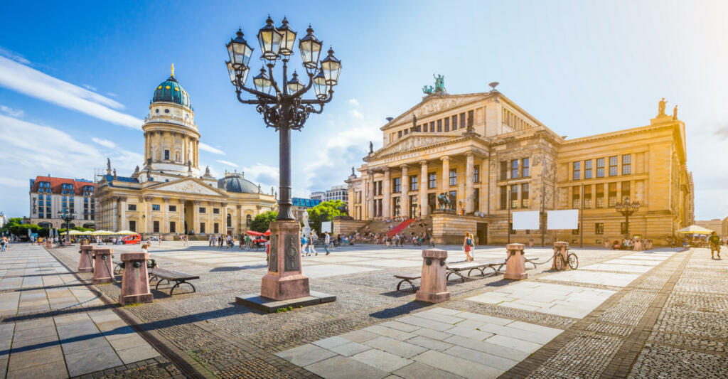 Panoramic view of famous Gendarmenmarkt square with Berlin Concert Hall and German Cathedral in golden evening light at sunset with blue sky and clouds in summer, Berlin Mitte district, Germany