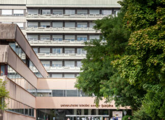 Kako je mogoče med zdravniško stavko opraviti več primerov, kot v času brez stavke? Picture of the main Slovenian hospital, univerzitetni klinicki centar ljubljana, the university clinical centar, zith a focus on its entrance and its main facade.