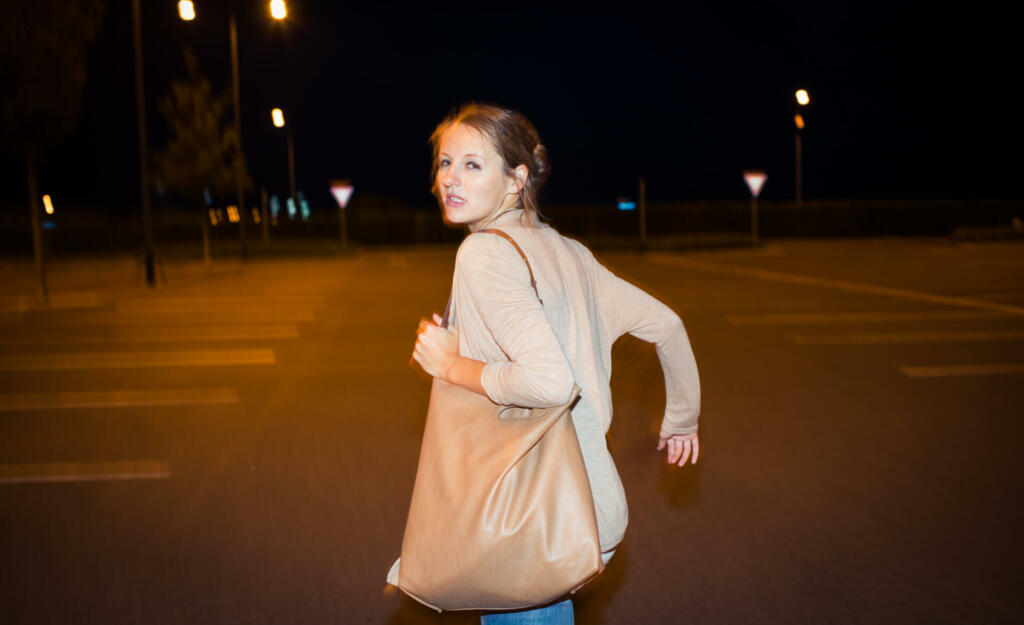 Scared young woman running from her pursuer in a deserted parking lot