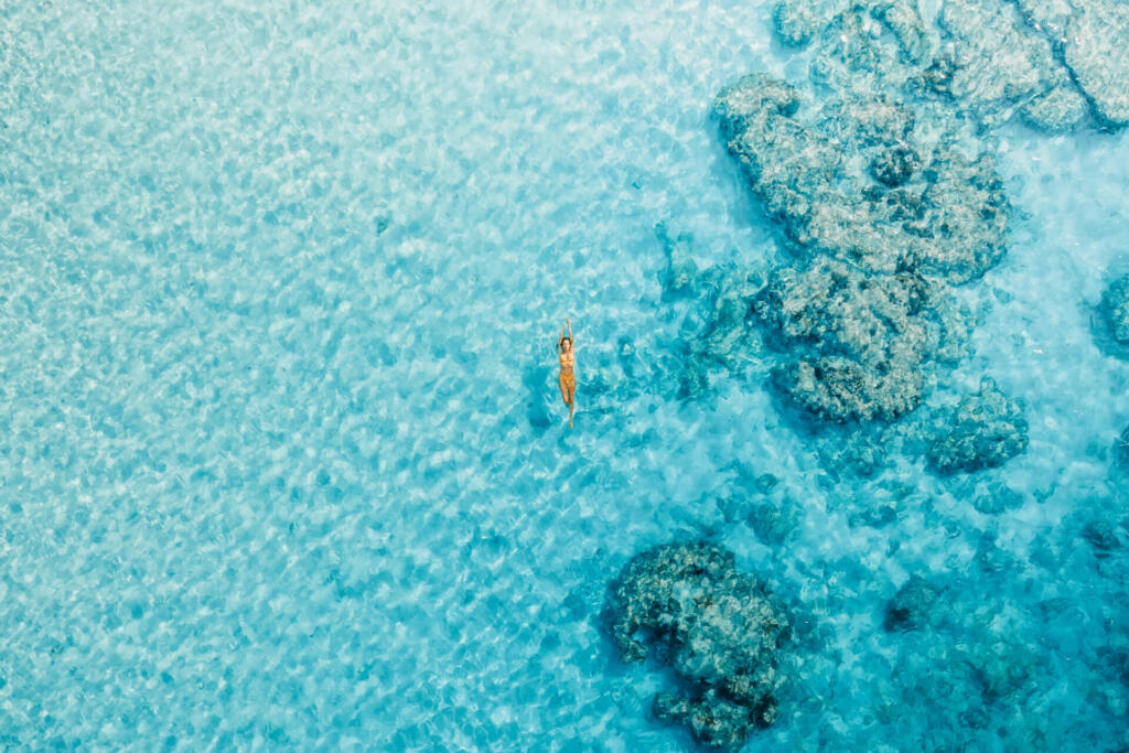 Woman swimming in blue ocean on her vacations. Aerial view, top view