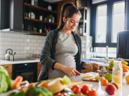 Young beautiful pregnant woman preparing healthy meal with fruites and vegetables