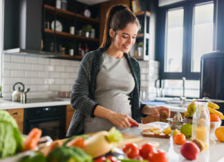 Zdravi prigrizki za noseče študentke (hitre in okusne ideje) Young beautiful pregnant woman preparing healthy meal with fruites and vegetables