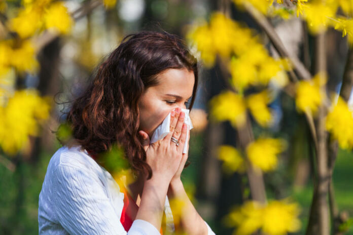 Young woman blowing her nose while being in the nature