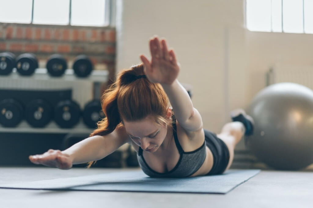 Young woman toning her abdominal muscles working out on a mat in a gym in a healthy active lifestyle concept