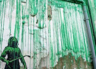 Umetnik Banksy opažen pred svojim grafitom: Ali je skrivnost njegove identitete razrešena? Figura Banksyjevega grafita na stavbi v okolici parka Finsbury v Londonu