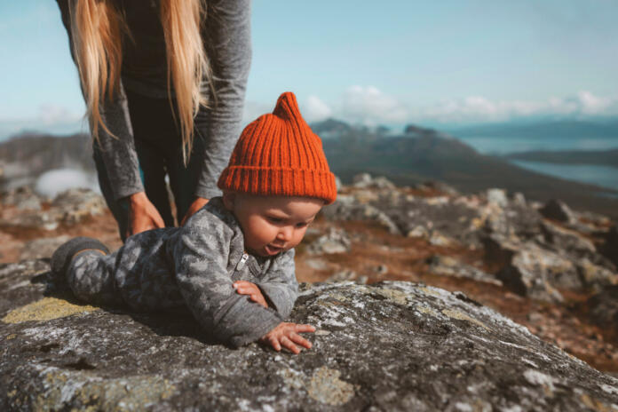 Baby learning crawling outdoor family vacation mother with child infant  wearing orange hat autumn season in Norway