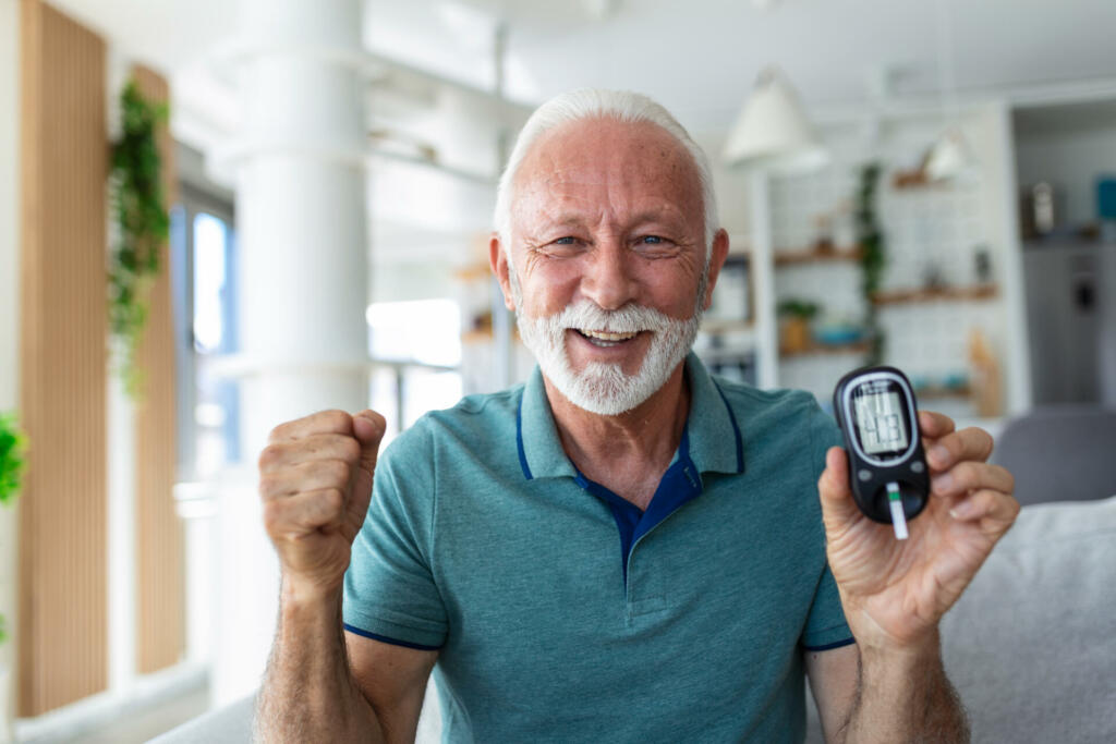 Blood sugar testing at home. Checking Blood Sugar Level At Home. Diabetic Checking Blood Sugar Levels. Senior man checking blood sugar level by glucometer and test stripe at home
